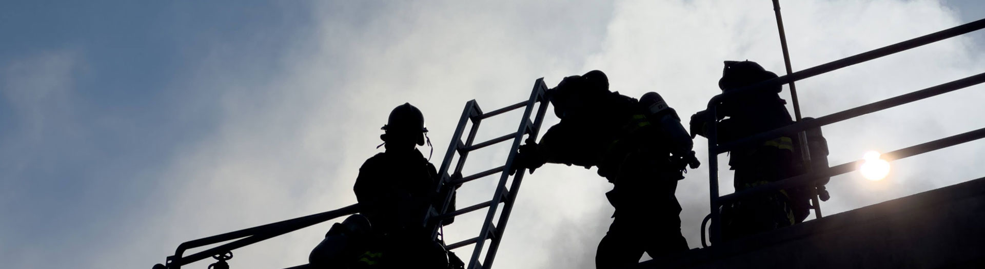 3 fire fighters silhouetted atop a roof