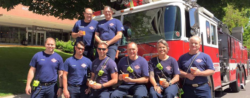 eight fire fighters sit eating ice cream in front of fire truck